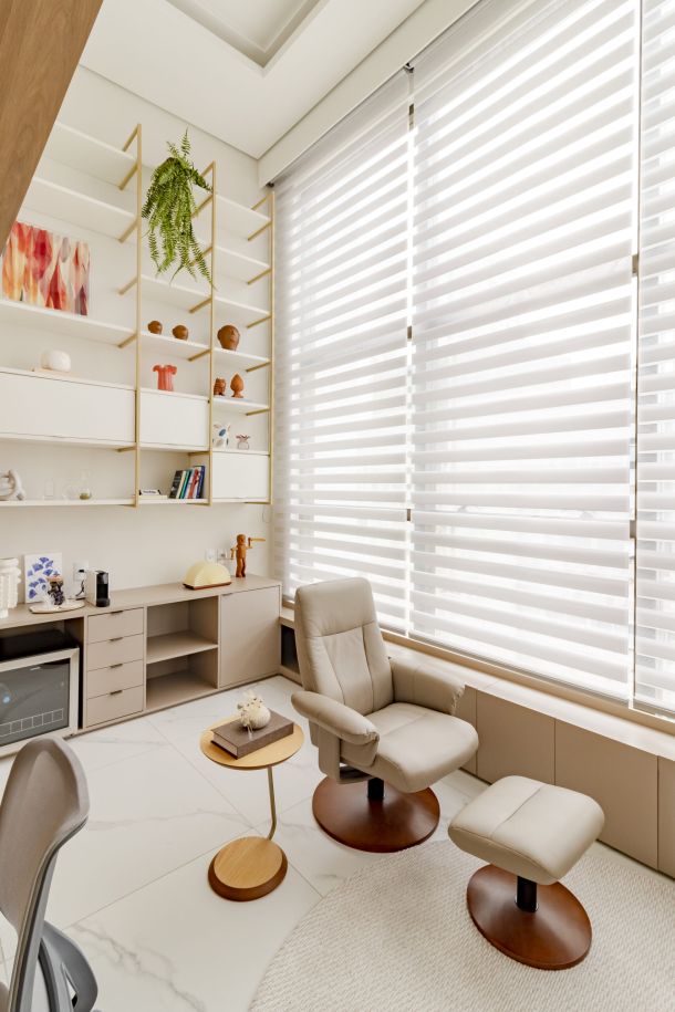 Ambiente aconchegante e moderno com cortina Mystique da Uniflex, projetado pela arquiteta Elisa Coelho. O espaço integra home office e área de descanso, com tons neutros, detalhes em madeira e iluminação natural suave filtrada pela cortina.
