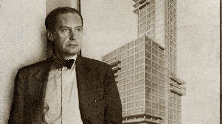 Retrato de Walter Gropius, fundador da Bauhaus, ao lado de edifício modernista com formas geométricas